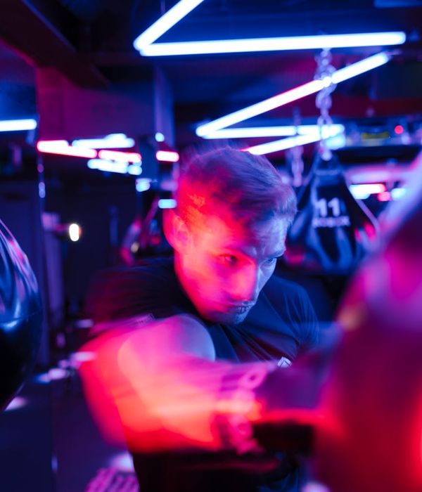 Man performing a functional strength exercise with neon purple lighting.